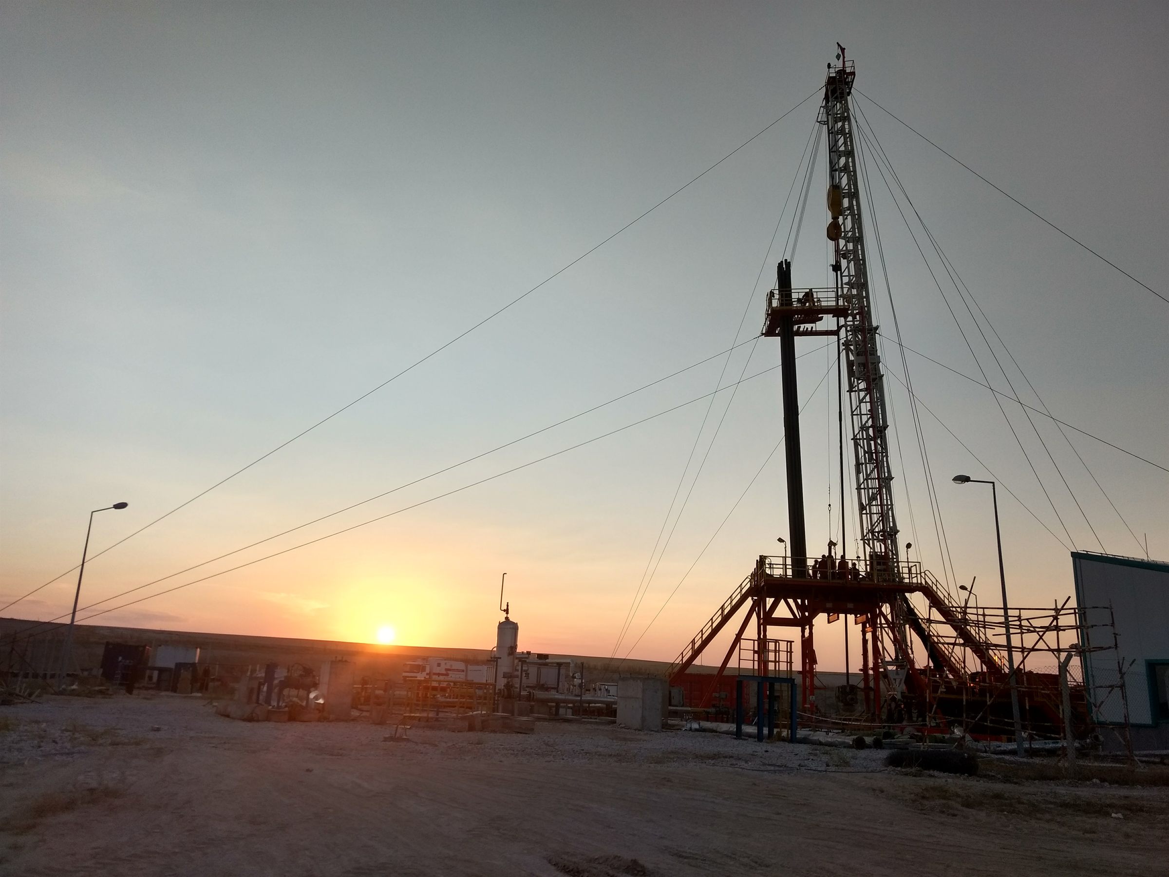 Workover rig at sunset on a producing oilfield